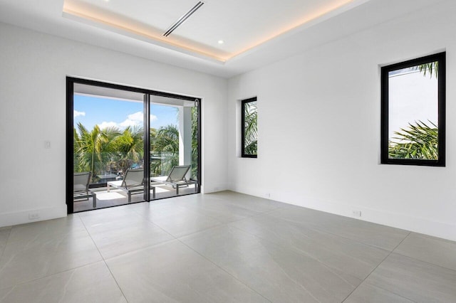 empty room featuring recessed lighting, a raised ceiling, and baseboards