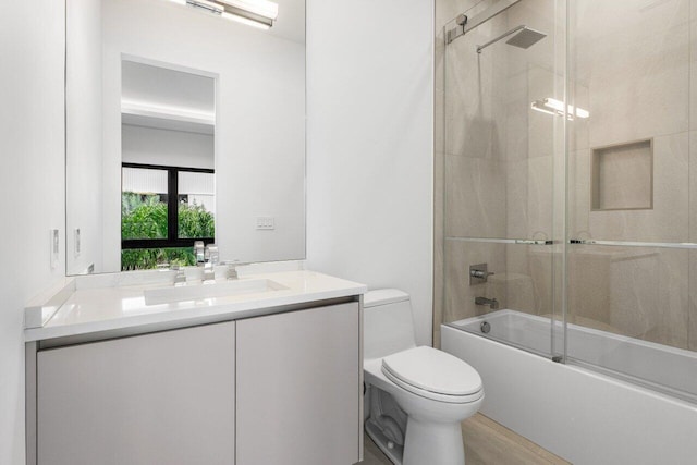 full bathroom featuring toilet, combined bath / shower with glass door, wood finished floors, and vanity