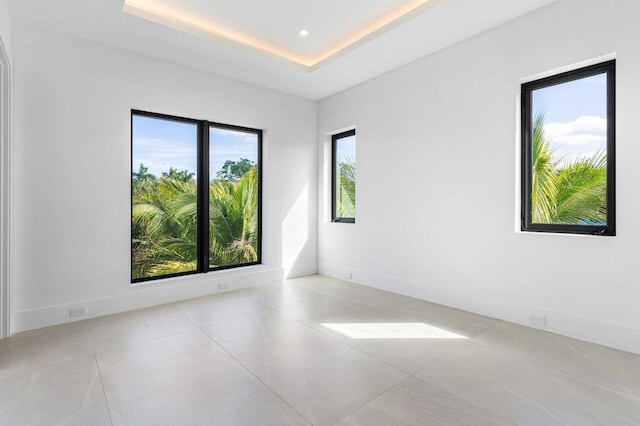 spare room with light tile patterned floors, a tray ceiling, recessed lighting, and baseboards