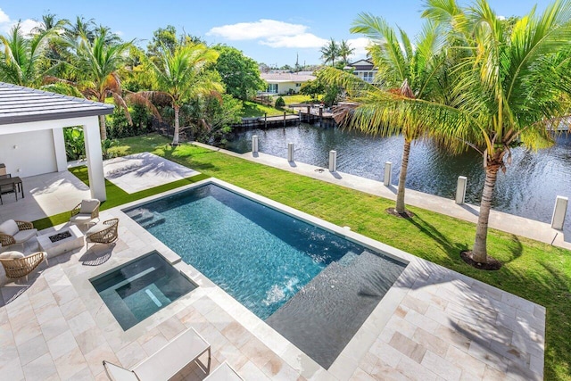 view of swimming pool with a patio, a pool with connected hot tub, a water view, a lawn, and a boat dock