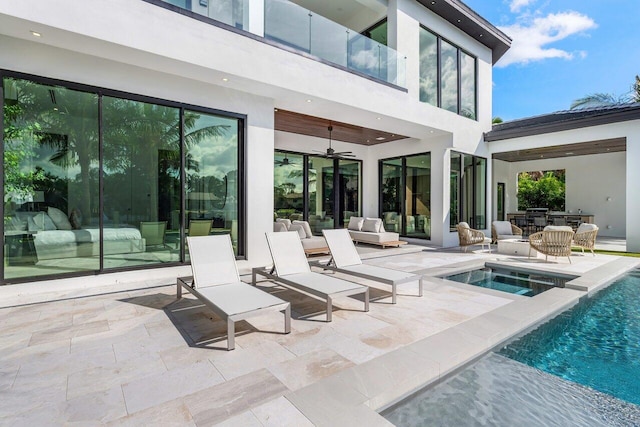 exterior space featuring a patio, a balcony, an in ground hot tub, a ceiling fan, and an outdoor pool