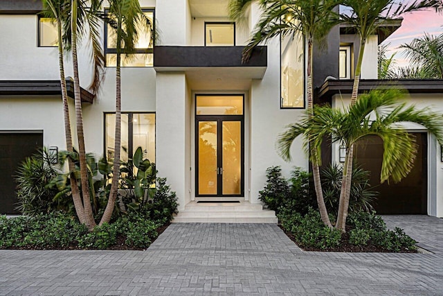 view of exterior entry featuring a garage and stucco siding