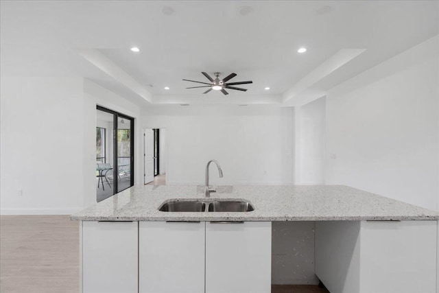 604 Lake Ave, Lehigh Acres, FL 33972 - kitchen with white cabinetry, light stone countertops, light hardwood / wood-style floors, sink, and a raised ceiling