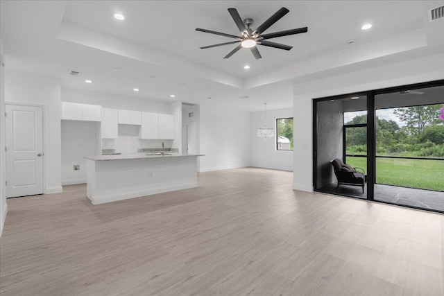 604 Lake Ave, Lehigh Acres, FL 33972 - unfurnished living room with a raised ceiling, light hardwood / wood-style flooring, and ceiling fan with notable chandelier