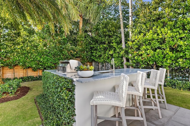 view of patio with exterior bar, a grill, and an outdoor kitchen