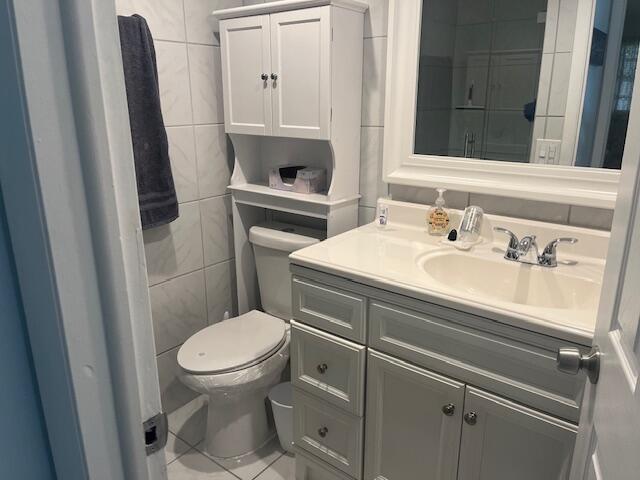 bathroom with tile patterned floors, vanity, toilet, and tile walls