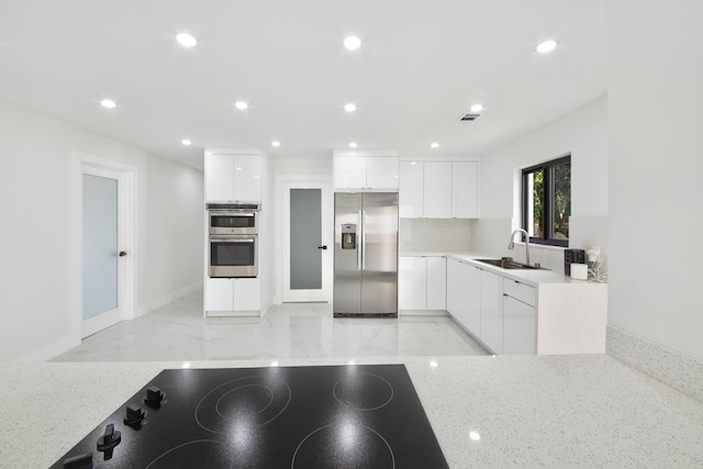 kitchen with recessed lighting, appliances with stainless steel finishes, white cabinets, a sink, and modern cabinets