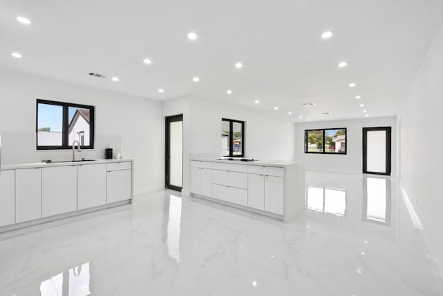 kitchen with visible vents, modern cabinets, marble finish floor, white cabinetry, and a sink