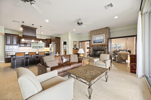 living room with a fireplace, ceiling fan, and a healthy amount of sunlight