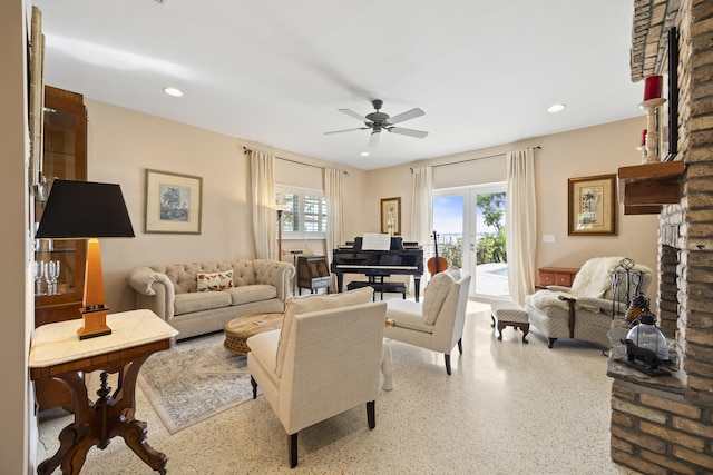 living room with a fireplace, french doors, and ceiling fan