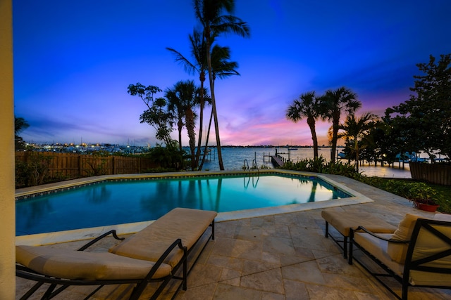 pool at dusk with a patio and a water view