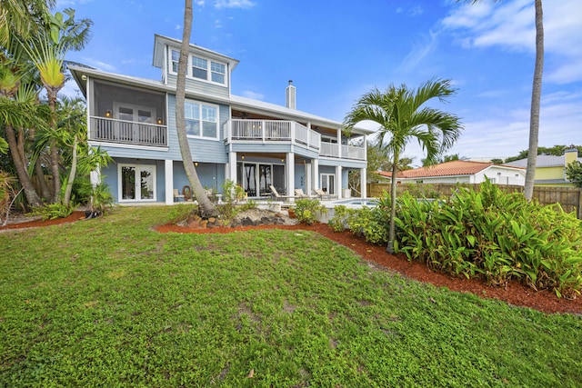 rear view of property with a fenced in pool, a lawn, french doors, and a balcony