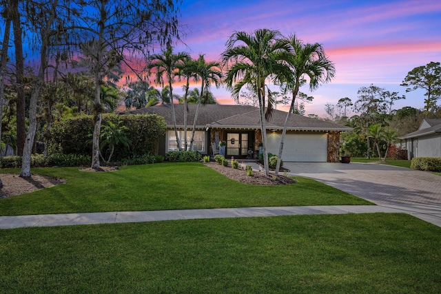 single story home featuring a garage and a yard