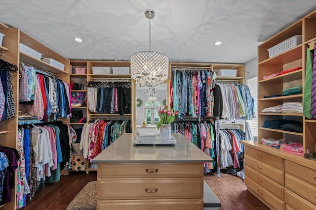 spacious closet with an inviting chandelier and dark hardwood / wood-style flooring