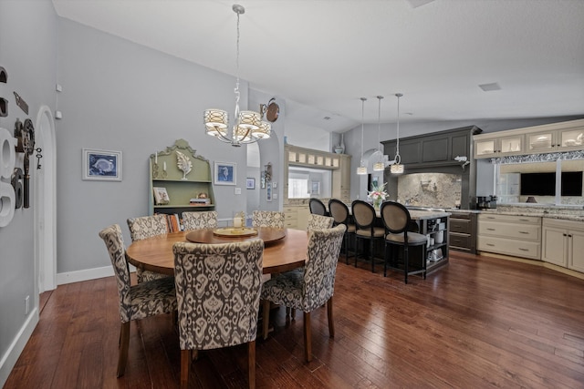 dining area with a notable chandelier, dark wood-type flooring, and vaulted ceiling