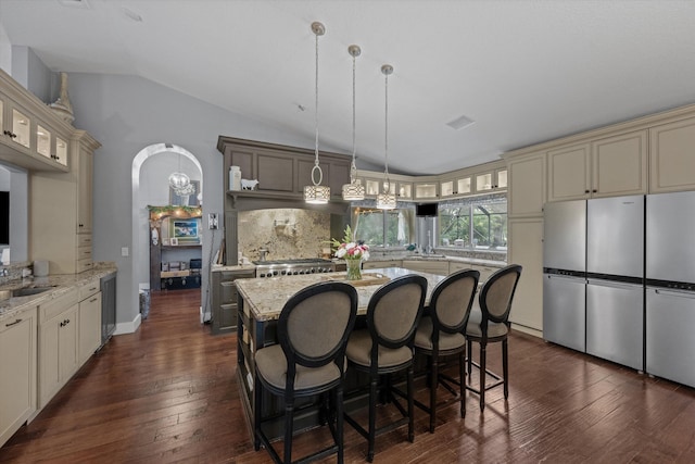 kitchen with cream cabinetry, tasteful backsplash, decorative light fixtures, vaulted ceiling, and dark hardwood / wood-style flooring