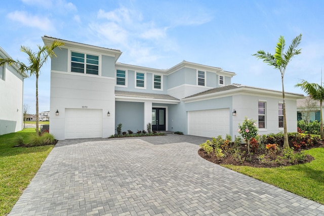 view of front of house with decorative driveway, an attached garage, french doors, and stucco siding