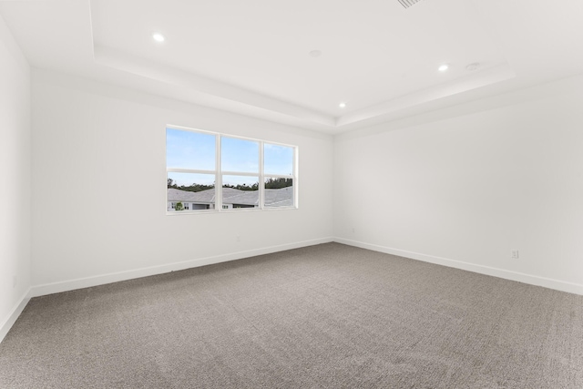 spare room featuring a tray ceiling, recessed lighting, carpet flooring, and baseboards