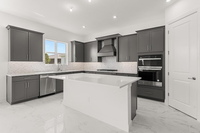 kitchen with a center island, marble finish floor, decorative backsplash, appliances with stainless steel finishes, and wall chimney exhaust hood