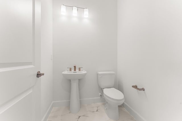 bathroom featuring toilet, marble finish floor, and baseboards