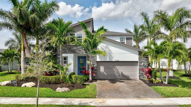 view of front of home with a garage, stone siding, decorative driveway, and stucco siding