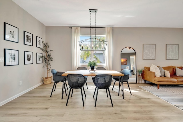 dining space with an inviting chandelier, light wood-style flooring, and baseboards