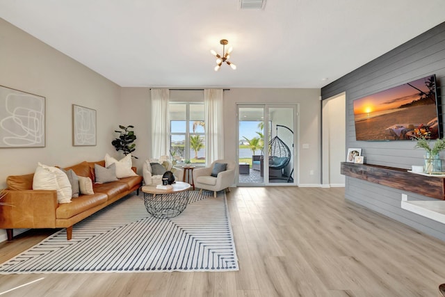 living room featuring visible vents, an inviting chandelier, wood walls, wood finished floors, and baseboards