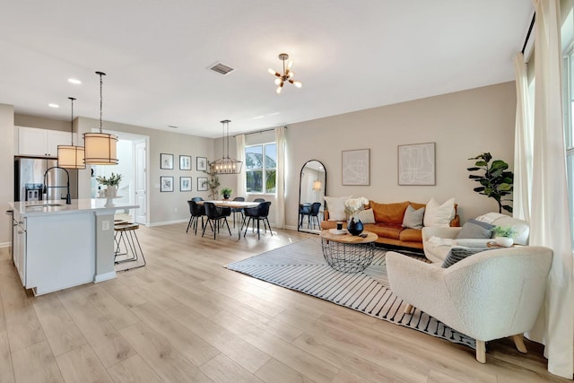 living area featuring recessed lighting, visible vents, baseboards, light wood finished floors, and an inviting chandelier