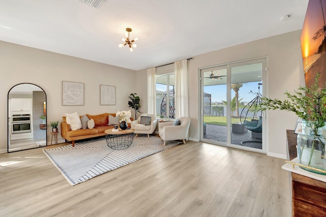 living room with light wood-style flooring, visible vents, a chandelier, and baseboards