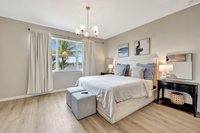 bedroom with baseboards, a notable chandelier, and light wood finished floors