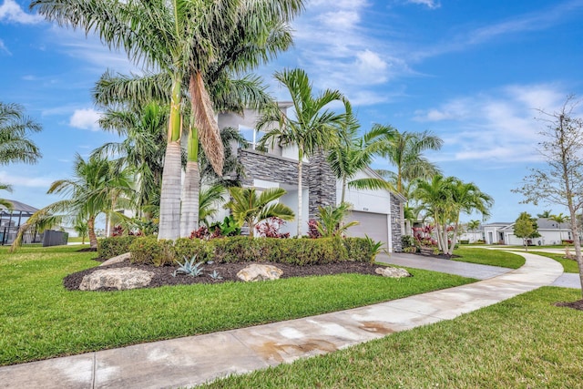 view of front of house featuring a front yard, stone siding, driveway, and an attached garage