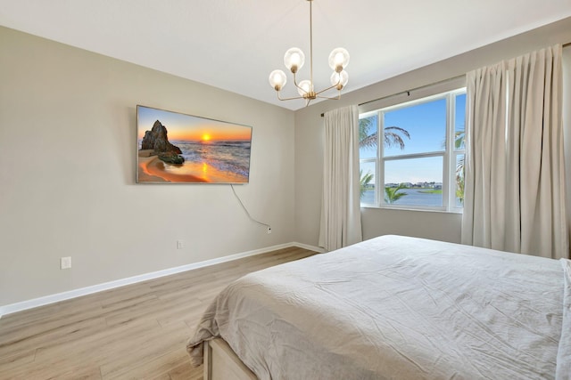 bedroom with an inviting chandelier, baseboards, and wood finished floors