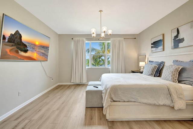 bedroom with light wood-type flooring, an inviting chandelier, and baseboards