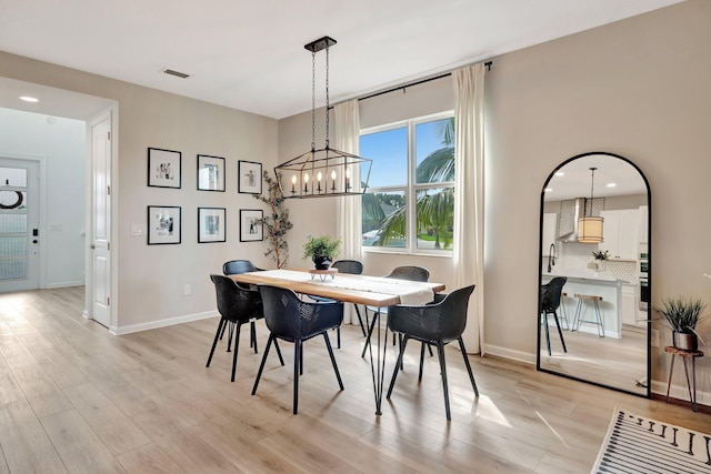 dining space with light wood finished floors, visible vents, and baseboards