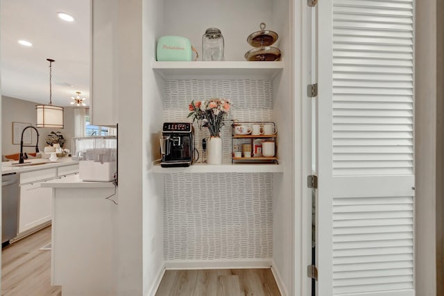 interior space with baseboards, light wood-type flooring, a sink, and recessed lighting