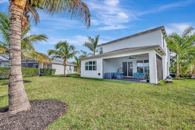 back of property featuring ceiling fan, a lawn, and stucco siding