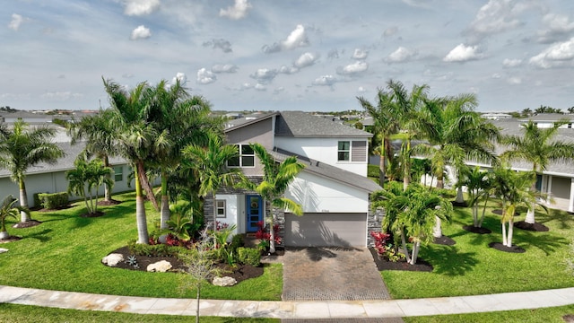 view of front facade with a front lawn, decorative driveway, an attached garage, and stucco siding