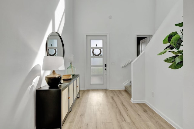 foyer with stairs, baseboards, and light wood-style floors