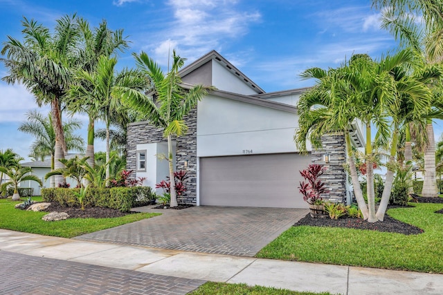 view of front of property with stone siding, decorative driveway, an attached garage, and stucco siding