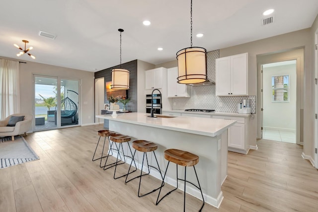 kitchen featuring light wood-style floors, decorative backsplash, gas stovetop, and a kitchen breakfast bar