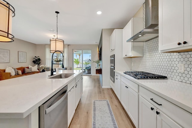 kitchen with tasteful backsplash, appliances with stainless steel finishes, light countertops, wall chimney range hood, and white cabinetry