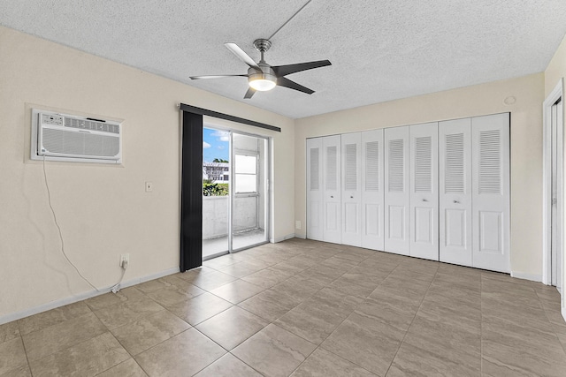 unfurnished bedroom with an AC wall unit, a ceiling fan, access to outside, a textured ceiling, and baseboards