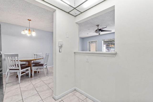 dining area with light tile patterned flooring, ceiling fan with notable chandelier, a textured ceiling, and baseboards