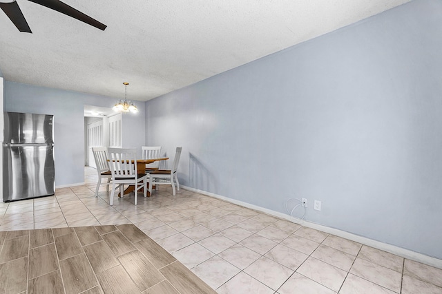 dining space featuring light tile patterned flooring, ceiling fan with notable chandelier, baseboards, and a textured ceiling