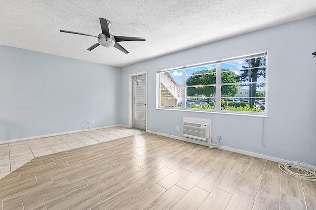 unfurnished room featuring an AC wall unit, a textured ceiling, wood finished floors, baseboards, and ceiling fan