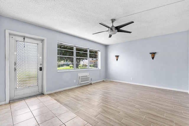 empty room featuring a wall unit AC, wood finished floors, a ceiling fan, and a textured ceiling