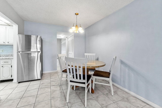 dining room featuring light tile patterned flooring, a chandelier, a textured ceiling, and baseboards