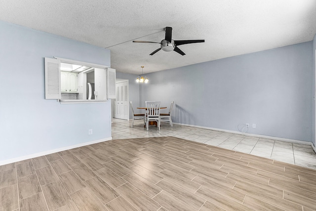 interior space featuring wood finish floors, baseboards, a textured ceiling, and ceiling fan with notable chandelier