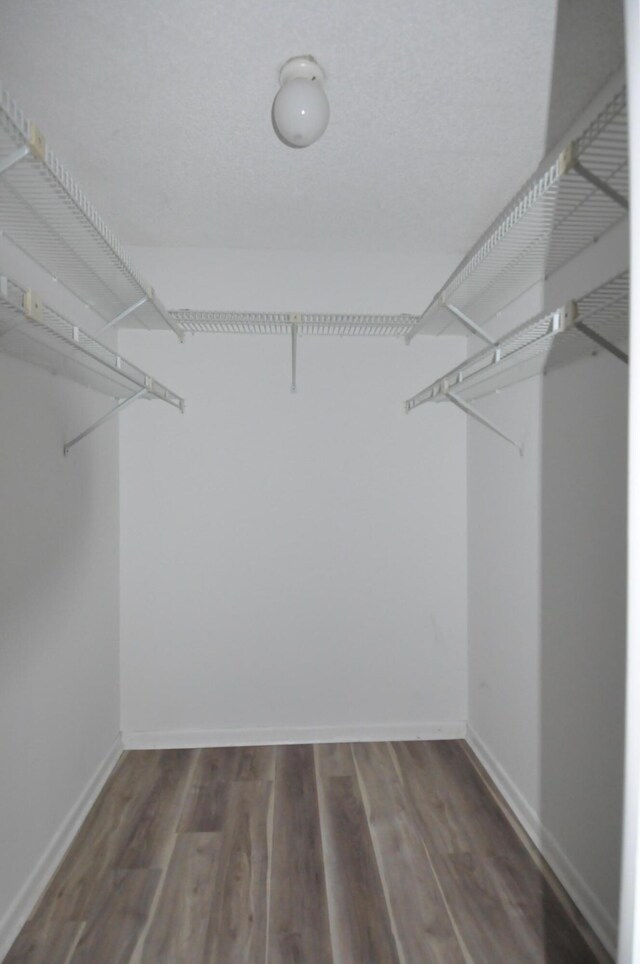 unfurnished bedroom featuring baseboards, ceiling fan, wood finished floors, a textured ceiling, and a closet