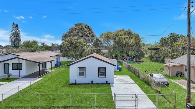 view of side of home with concrete driveway, a yard, a fenced front yard, and stucco siding